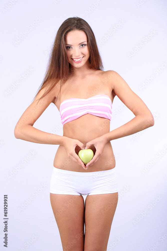 Fototapeta premium Beautiful young woman with green apple on grey background