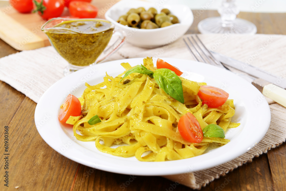 Delicious pasta with pesto on plate on table close-up