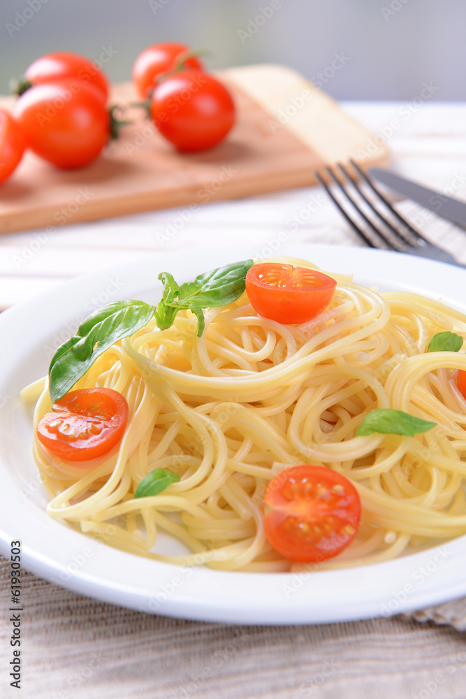 Delicious spaghetti with tomatoes on plate on table close-up Delicious spaghetti with tomatoes on plate on table close-up