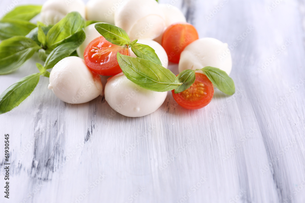 Tasty mozzarella cheese with basil and tomatoes, on wooden Tasty mozzarella cheese with basil and tomatoes, on wooden