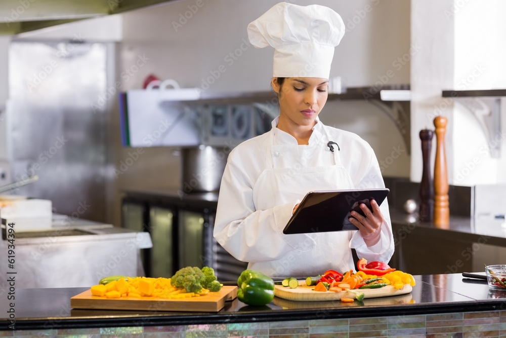 Female chef using digital tablet while cutting vegetables Female chef using digital tablet while cutting vegetables