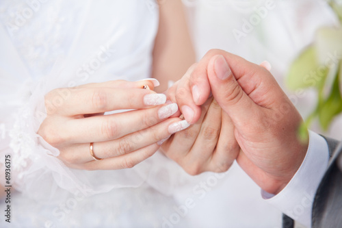 Closeup shot of young bride putting wedding ring on grooms hands