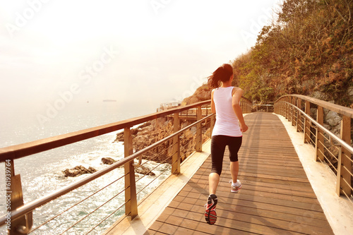 fitness young woman running seaside wooden bridge
