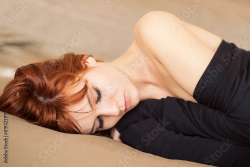 Fotografija Sensual young red head woman portrait while lying on bed in hote