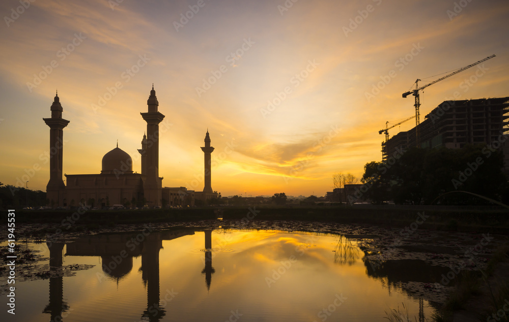 Silhouette mosque  and building under construction at sunrise.