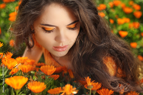 Beauty portrait. Eye Makeup. Beauty Girl over marigold flowers f © Victoria Andreas