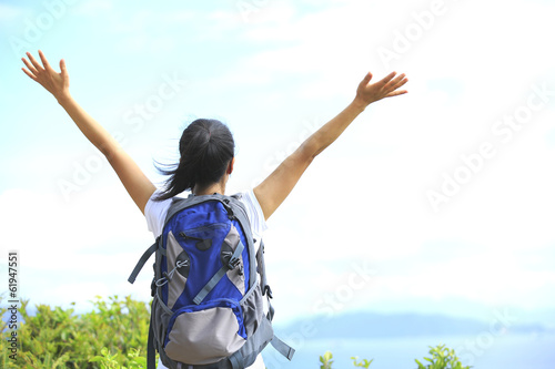 cheering woman hiker open arms at seaside mountain peak