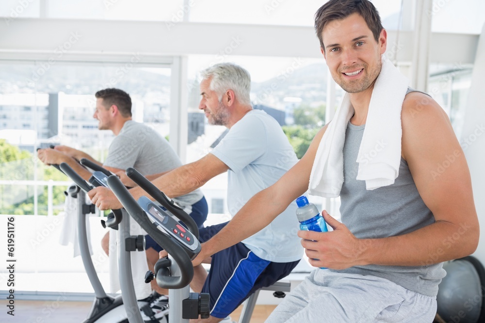 Man on exercise bike holding water bottle Man on exercise bike holding water bottle
