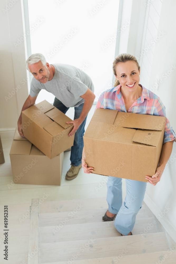 Happy couple carrying cardboard moving boxes Happy couple carrying cardboard moving boxes