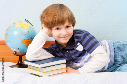 The boy lean elbow on stack of books
