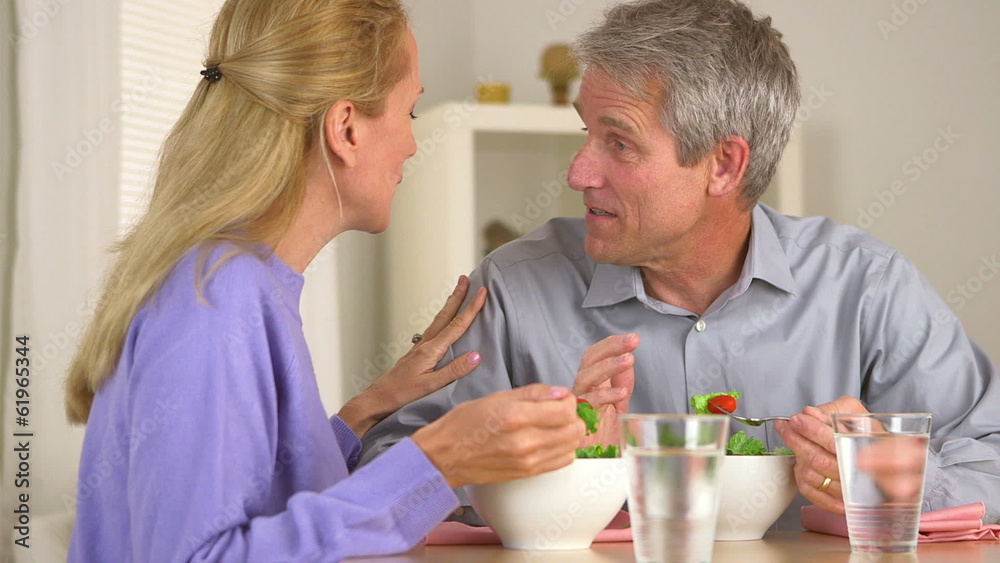 Mature couple talking and eating salad