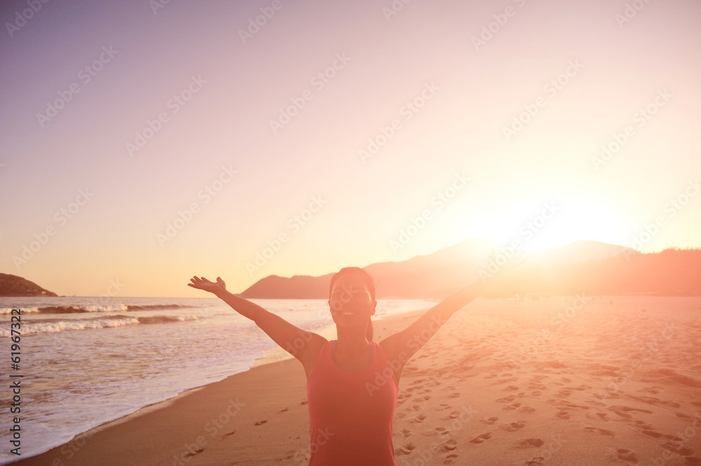 Fototapeta premium woman open arms at sunrise/sunset beach
