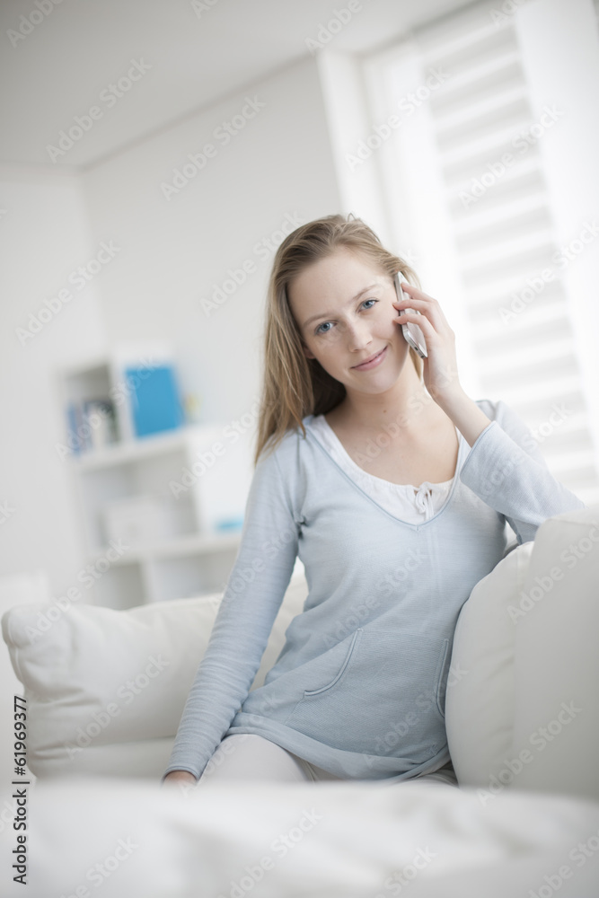 Obraz premium beautiful young woman sitting on a sofa and calling a friend wit