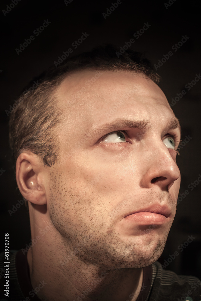 Young confused Caucasian man portrait on dark background Young confused Caucasian man portrait on dark background