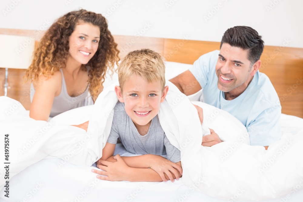 Cute young family smiling at camera on bed Cute young family smiling at camera on bed