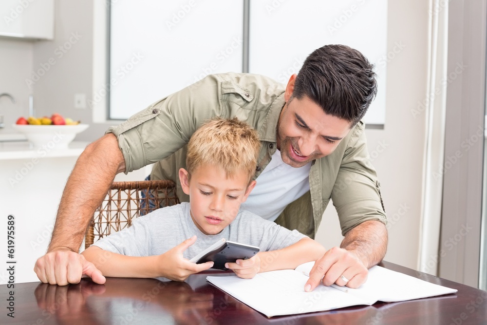 Smiling father helping son with math homework at table Smiling father helping son with math homework at table
