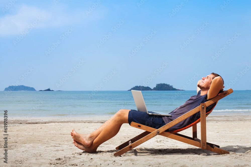 happy business man with laptop relaxing on the beach