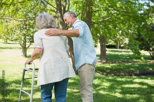 Mature man assisting woman with walker at park