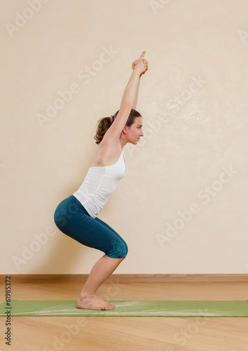 Caucasian woman is practicing yoga at studio (utkatasana) photo