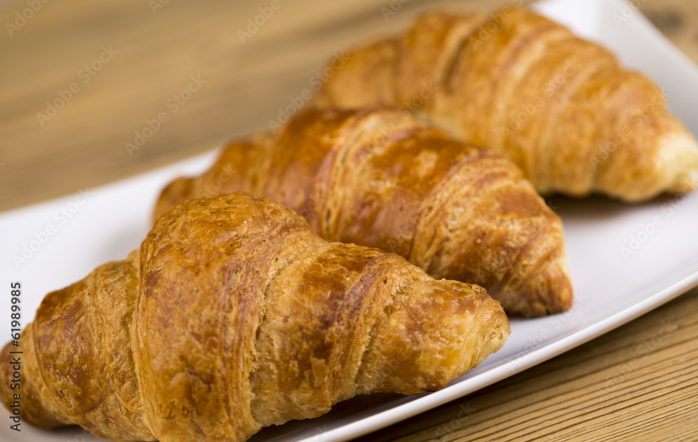 Hot croissants with chocolate on wooden table