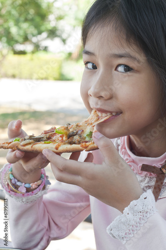 Little Asian girl enjoy eating pizza.