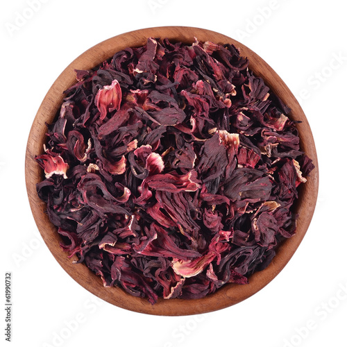 Dried petals of hibiscus in a wooden bowl on a white