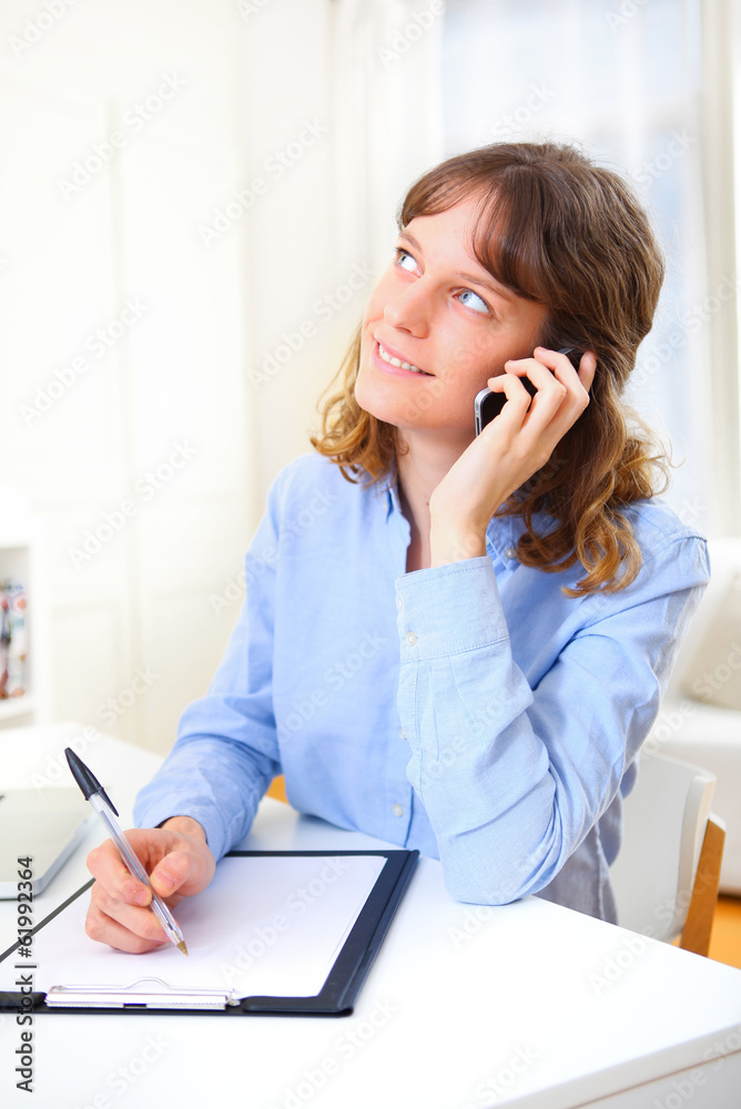 Young attractive business woman copying data on paper while phon Young attractive business woman copying data on paper while phon