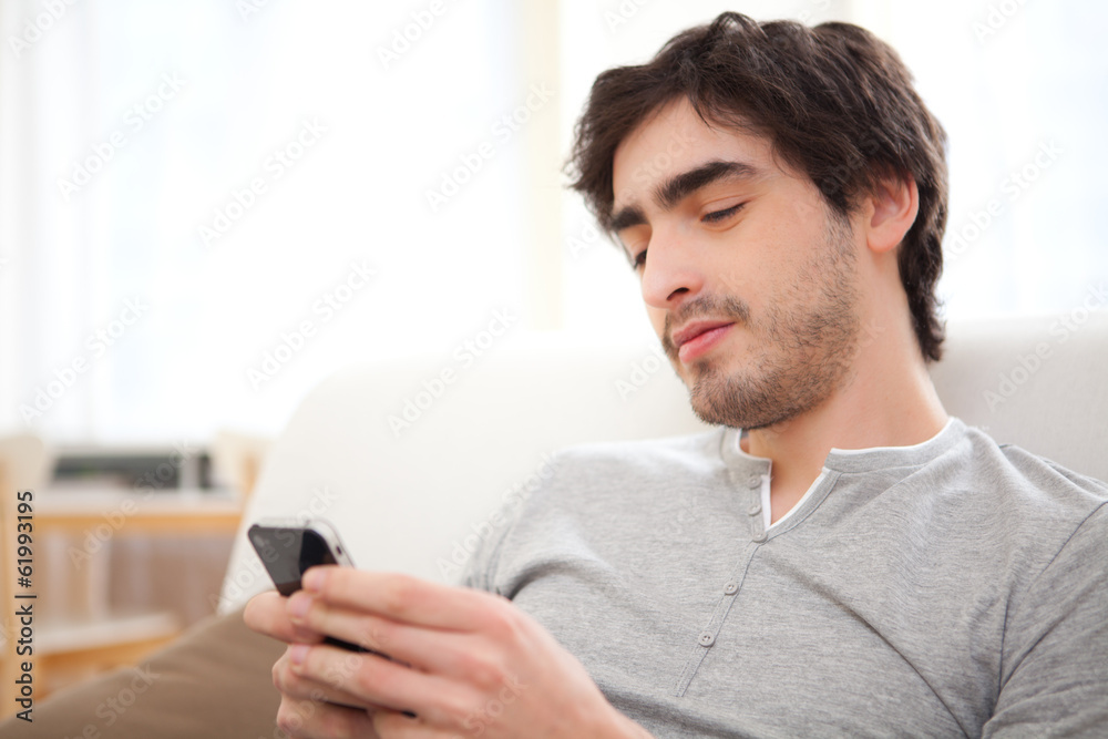 Young relaxed man writting text in the sofa Young relaxed man writting text in the sofa