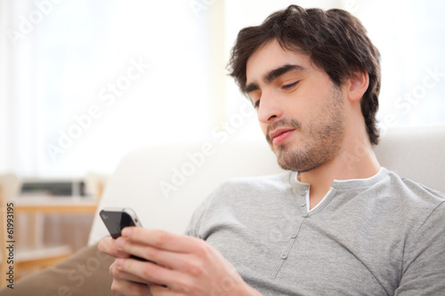 Young relaxed man writting text in the sofa