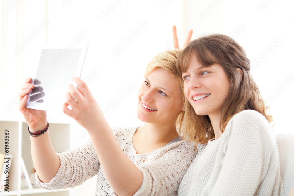 Girls on sofa taking selfie picture with tablet