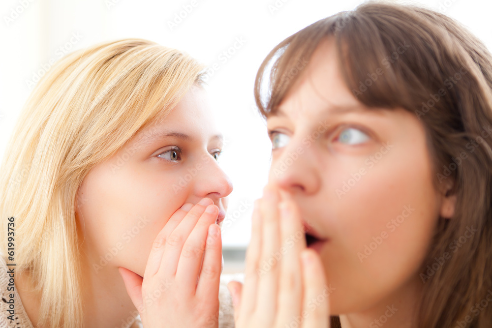 Blonde girl telling a secret to her best friend Blonde girl telling a secret to her best friend