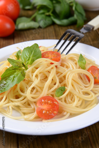 Delicious spaghetti with tomatoes on plate on table close-up