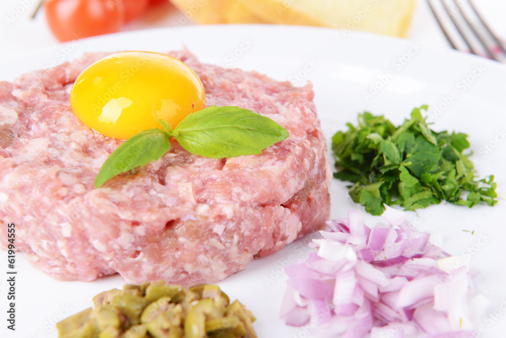 Delicious steak tartare with yolk on plate on table close-up