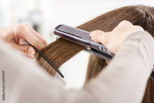 Hairdresser straightening long brown hair