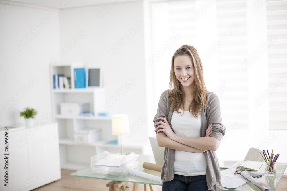 beautiful young woman arms crossed standing in front of his desk