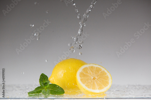 Лимон в брызгах воды на белом фоне