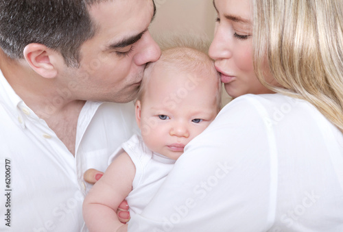 Young parents kissing baby