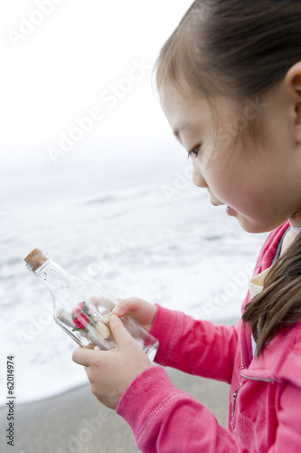 girl having bottle containing message in hand