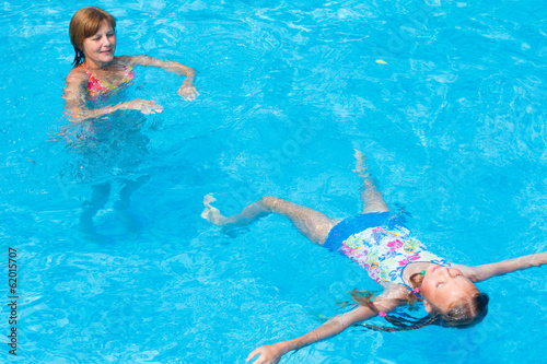 Mother train her daughter to swim in the pool. © wildman