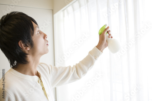 man spraying deodorant spray on curtain