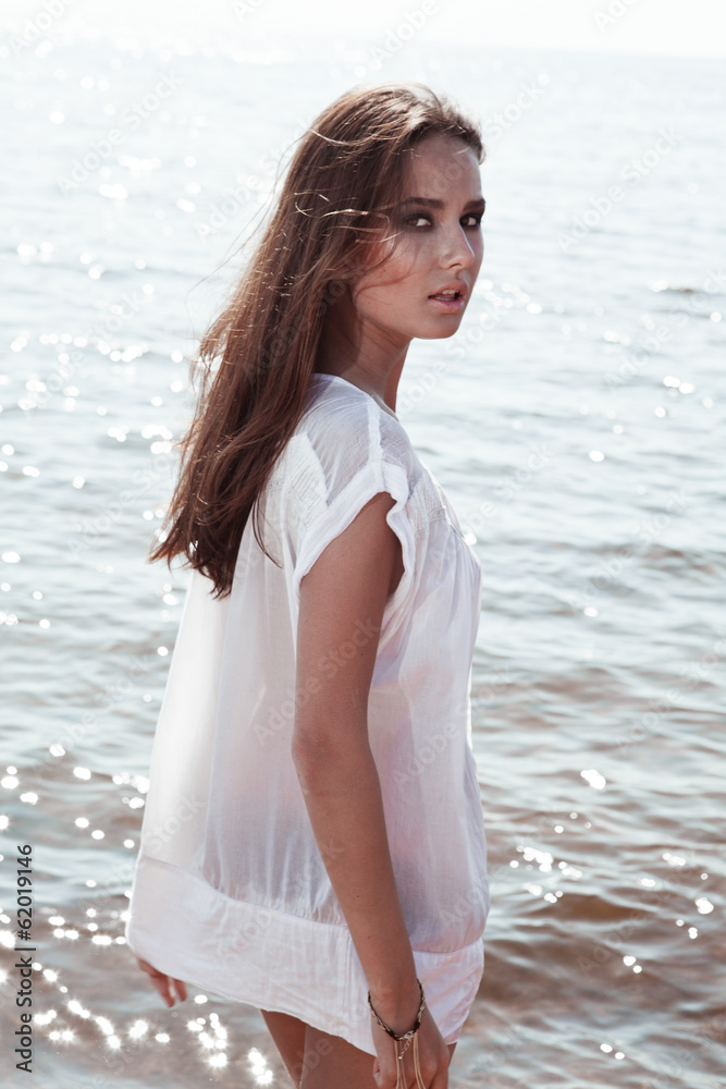 Young sexy brunette on the beach in wet t-shirt
