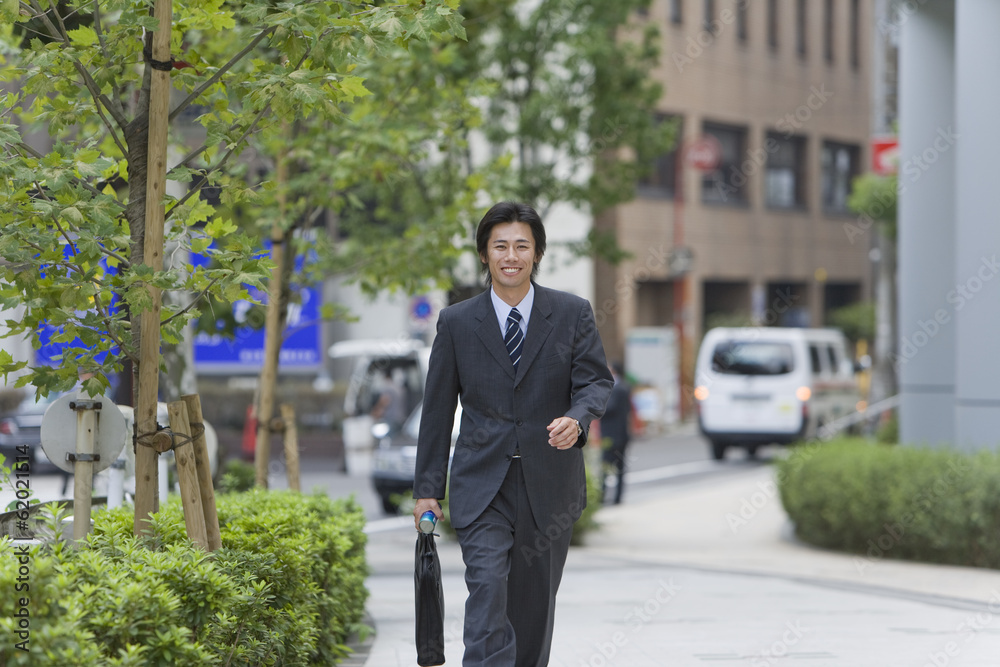 smiling business man walking on sidewalk