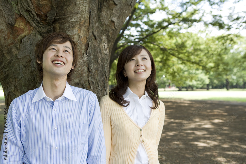 smiling couple standing still under the tree