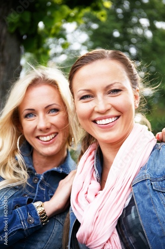 Two beautiful young women on a bench in a park