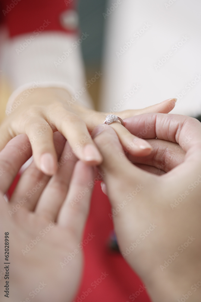 man putting a ring on woman's hand