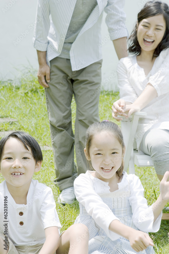 smiling family sitting down on lawn smiling family sitting down on lawn