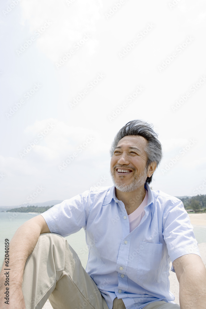 man sitting on beach looks at view man sitting on beach looks at view