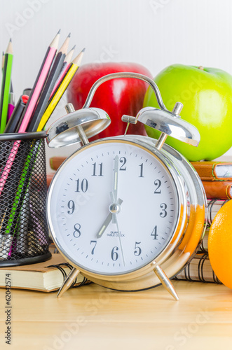 Back to school , note book , clock , pencil , apple on wood tabl