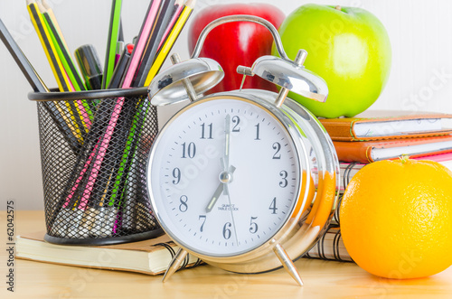 Back to school , note book , clock , pencil , apple on wood tabl