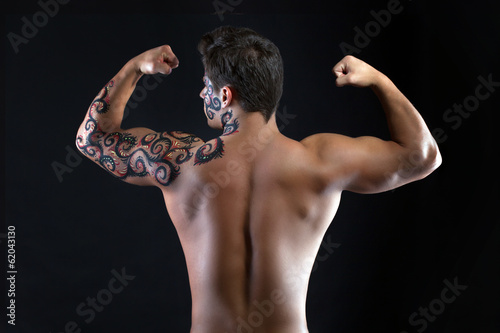 Strong guy posing shirtless, back to camera